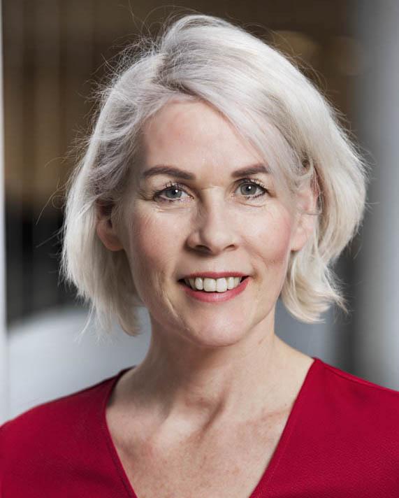 andrea evers. a close up picture of a woman smiling in the camera. She is wearing a red shirt and has grey hair