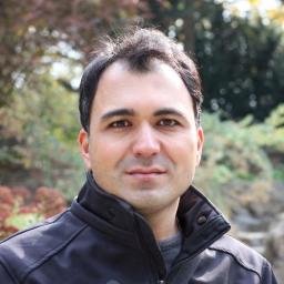 a picture of Saleh, a man standing in front of a forest-like background, wearing a dark leather jacket. He has dark hir. 